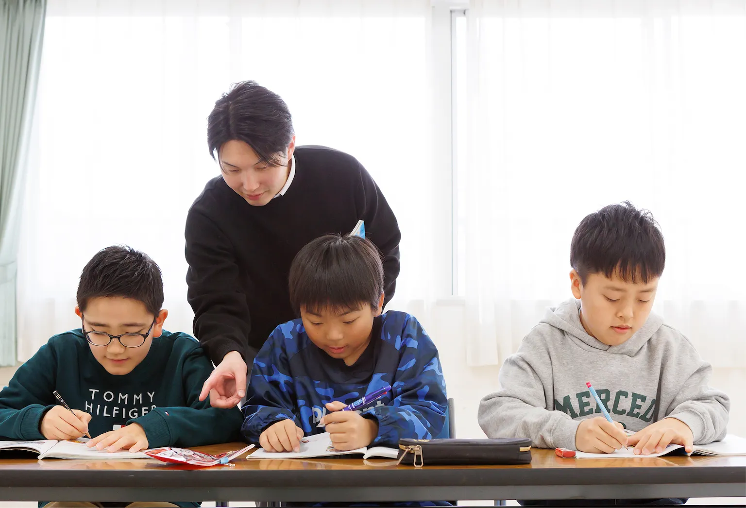 講師のサポートを受けながら英語の問題に取り組む小学生