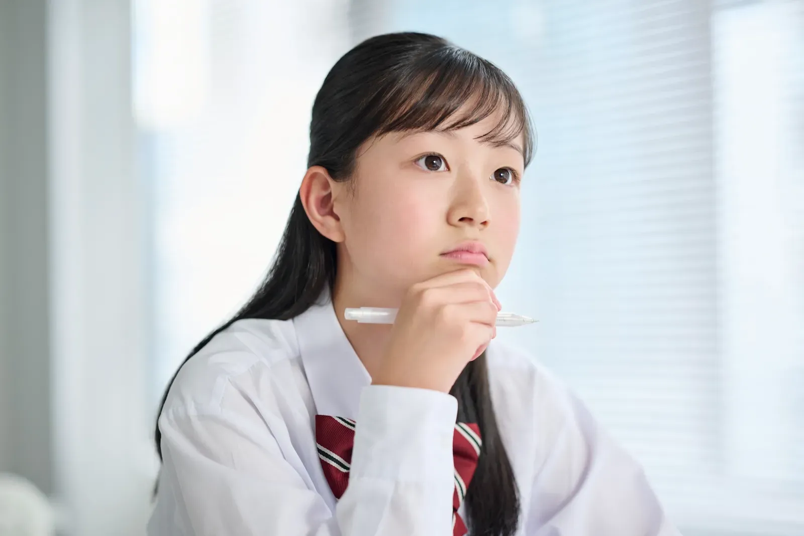 ペンを手に考える女子中学生