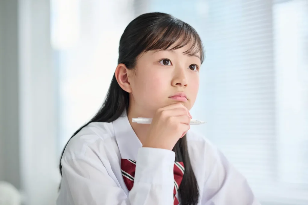 ペンを手に考える女子中学生